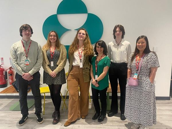 Six people with red lanyards standing in line